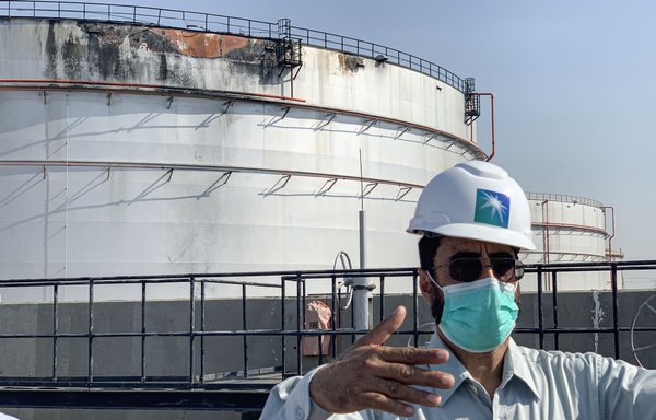 In this file photo from November 24, an employee at the Saudi Aramco oil facility in Jeddah stands near a damaged silo, a day after the Houthis launched a missile attack on the facility, triggering an explosion and a fire in a fuel tank. [Fayez Nureldine/AFP]