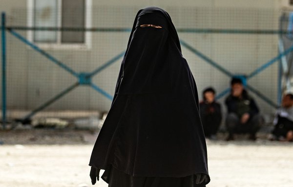 A woman pictured in al-Hol camp on March 3 is dressed in a niqab and gloves, in compliance with the strict dress code enforced by self-appointed hesba ('religious police') units. [Delil Souleiman/AFP]