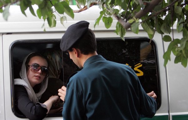 An Iranian morality police force member speaks with a woman after she was arrested for 'inappropriate hejab'. [Behrouz Mehri/AFP]