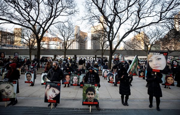 Demonstrators hold signs with images of the victims of the downed Ukraine International Airlines Flight 752, which was shot down near Tehran by Iran's IRGC, as family and friends gather to take part in a march to mark the first anniversary, in Toronto, Canada, on January 8. [Cole Burston/AFP]