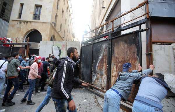 Lebanese demonstrators try to breach a fortified gate, leading to the Lebanese Parliament building, in downtown Beirut on March 13, 2021, during a protest against the political system. Many see Hizbullah as the main reason for the country's economic collapse. [Anwar Amro/AFP]