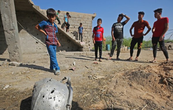 Iraqi youths last September look at damage to a house hit by an Iranian-made rocket near Baghdad airport. [Ahmad al-Rubaye/AFP]