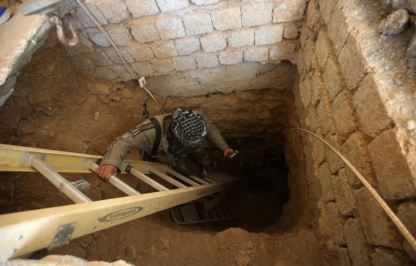 An Iraqi militia member looks down an underground tunnel previously used by ISIS near Tal Afar, Iraq. Iran-backed militias have been using ISIS tunnels to smuggle arms into Syria from Iraq. [AHMAD AL-RUBAYE / AFP]