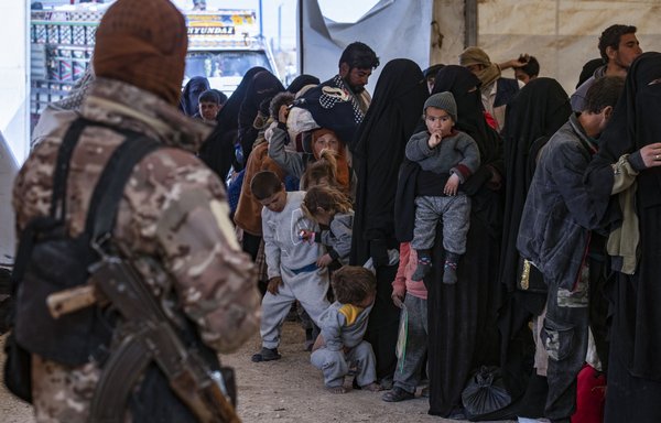 A member of the Kurdish security forces watches as a group of Syrian families is released from al-Hol camp, which holds suspected relatives of ISIS, on March 18. [Delil Souleiman/AFP]