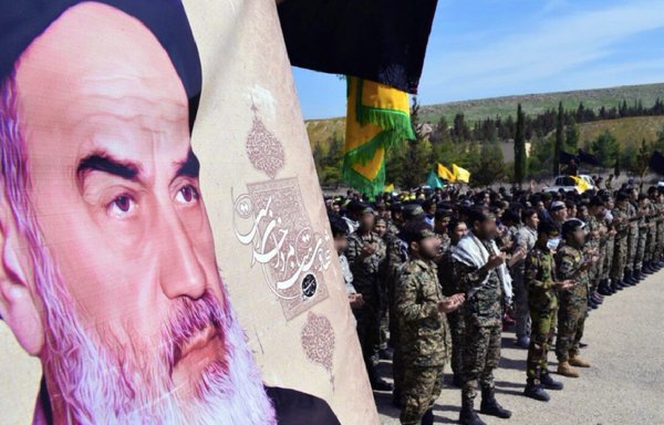 Members of the Iran-backed Fatemiyoun Division gather in Aleppo, Syria, last March beside a photo of Ayatollah Khomeini. Swearing loyalty to the Supreme Leader and the idea of the Guardianship of the Jurist is required to be part of the various Iran-backed militias in the region. [File]