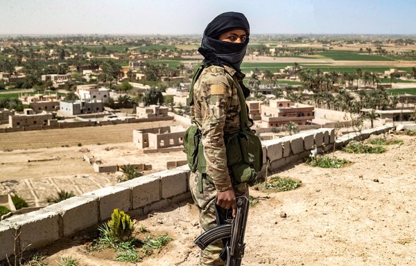 A fighter with the Syrian Democratic Forces (SDF) stands guard on a hilltop overlooking the village of al-Baghouz in Syria's northern Deir Ezzor province on March 24. [Delil Souleiman/AFP]