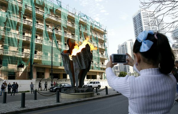 A child takes pictures of the memorial flame erected at the Beirut site of the assassination of former Lebanese Prime Minister Rafiq al-Hariri on February 14, 2016 -- the 11th anniversary of his death. [Anwar Amro/AFP]