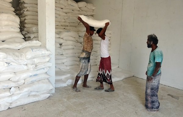 Displaced Yemenis receive humanitarian aid provided by the World Food Programme in the Khokha district of al-Hodeidah, on March 29. [Khaled Ziad/AFP]
