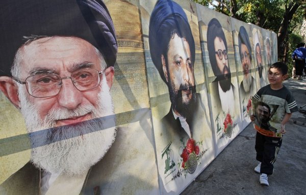 پسری لبنانی در تاریخ ۲۲ آبان ۱۳۹۹ از کنار تصاویر علمای شیعه لبنانی و ایرانی در شهر غازیه در جنوب صیدون، واقع در جنوب کشور، عبور می کند. [محمود زیات/ خبرگزاری فرانسه]