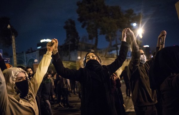 Iranians hold hands during a demonstration in front of Tehran's Amir Kabir University on January 11, 2020. [STR/AFP]