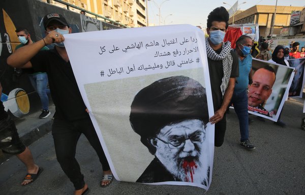Iraqi demonstrators attend a symbolic funeral on July 7 for Hisham al-Hashemi, the Iraqi analyst of extremist groups who was fatally shot outside his house in Baghdad the day before. The slogan partly reads in Arabic: "Khamenei is a killer, and his militias are wrongdoers." [Ahmad al-Rubaye/AFP]