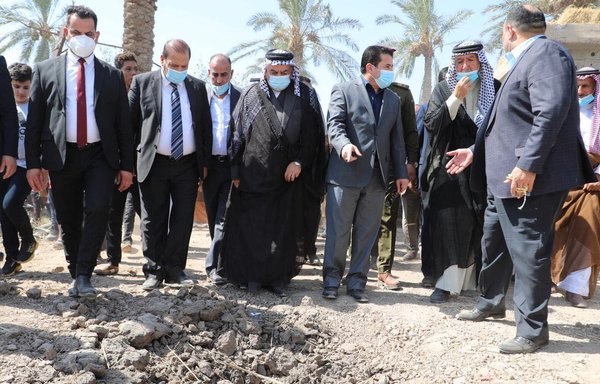 Iraqi officials and tribal leaders on September 29 point to a crater caused by a rocket attack blamed on pro-Iran militias on the town of al-Radwaniyah, near Baghdad. [Qassem Al-Araji/Facebook]