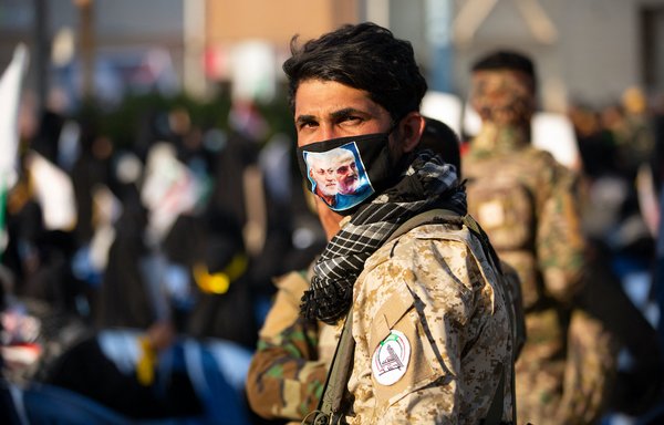 A member of Iraq's Popular Mobilisation Forces with the images of late Iraqi commander Abu Mahdi al-Muhandis and IRGC commander Qassem Soleimani on his mask. [Hussein FALEH / AFP]
