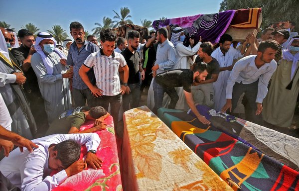 Iraqi men mourn over the coffins of a family killed when a rocket hit their home near Baghdad's airport during their funeral in al-Radwaniyah area on September 29. Three Iraqi children and two women from the same family were killed September 28 when a rocket targeting Baghdad airport fell instead on their home. [Ahmad al-Rubaye/AFP]