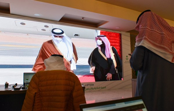 Journalists watch as Saudi Crown Prince Mohammed bin Salman welcomes the Emir of Qatar Tamim bin Hamad al-Thani on a screen in the media centre ahead of the 41st Gulf Co-operation Council summit in the Saudi city of al-Ula on January 5. [Fayez Nureldine/AFP]