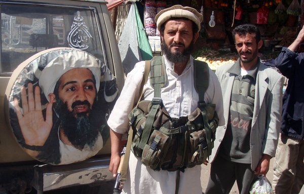 A fighter is seen standing in front of an image of Osama bin Laden, the late leader of al-Qaeda, in Rada, Yemen, January 21, 2012. [AFP Photo/STR]