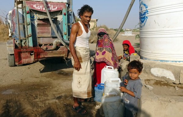 Yemenis fill their jerrycans with water at a make-shift camp for the internally displaced on April 17. [Khaled Ziad / AFP]