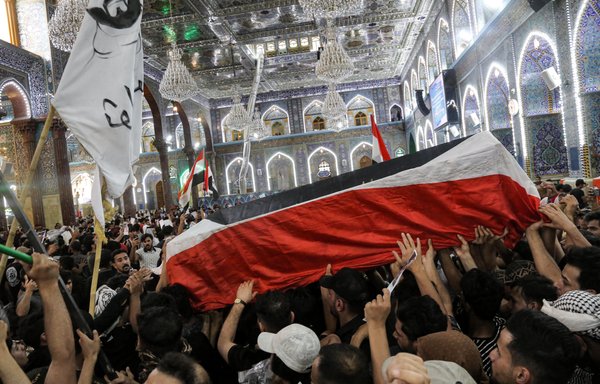 Mourners carry the coffin of Iraqi activist Ihab al-Wazni during his funeral at the Imam Hussein Shrine in Karbala on May 9. [Mohammed Sawaf/AFP]