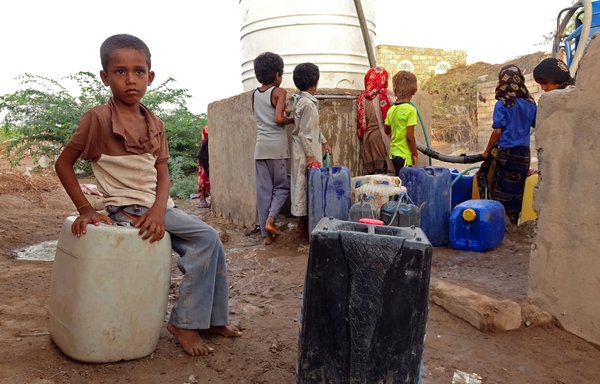Yemeni children fill their jerrycans with water at a make-shift camp for the internally displaced on May 7, 2021. [Khaled Ziad / AFP]