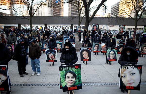 People hold signs with images of the victims of the downed Ukraine International Airlines flight PS752, which was shot down near Tehran by the IRGC, as family and friends gather to take part in a march to mark the first anniversary, in Toronto, Ontario, Canada, on January 8. [Cole Burston/AFP]