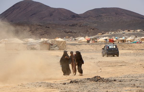 A woman walks with a boy and girl near a displacement camp on the outskirts of Yemen's northeastern city of Marib on March 28, as residents of the camp prepare to flee due to its proximity with battles between the Houthis and Yemeni government forces. [STR/AFP]