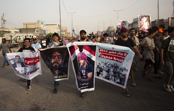 Iraqis hold banners demanding justice for slain activists and journalists during a demonstration in the southern city of Basra on May 25. [Hussein Faleh/AFP]