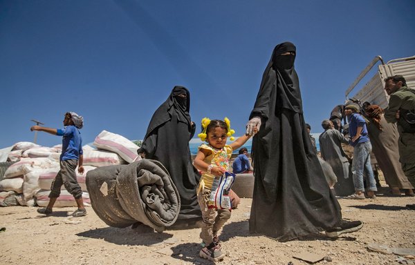 Women walk with children and belongings ahead of departure as another group of Syrian families is released from the Kurdish-run al-Hol camp, which holds relatives of suspected 'Islamic State of Iraq and Syria' (ISIS) group fighters, in the northeastern Syrian al-Hasakeh province, on May 11. [Delil Souleiman/AFP]