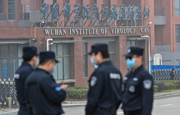 Security personnel stand guard outside the Wuhan Institute of Virology as members of the World Health Organisation (WHO) team investigating the origins of the COVID-19 pandemic visit the institute on February 3. [Hector Retamal/AFP]