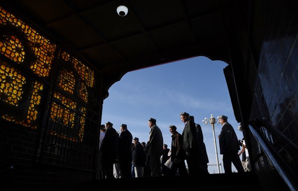 Muslim men make their way past a subway entrance after Eid al-Fitr prayers, marking the end of Ramadan, at the Id Kah mosque in Kashgar, Xinjiang region, China, June 5, 2019. [Greg Baker/AFP]