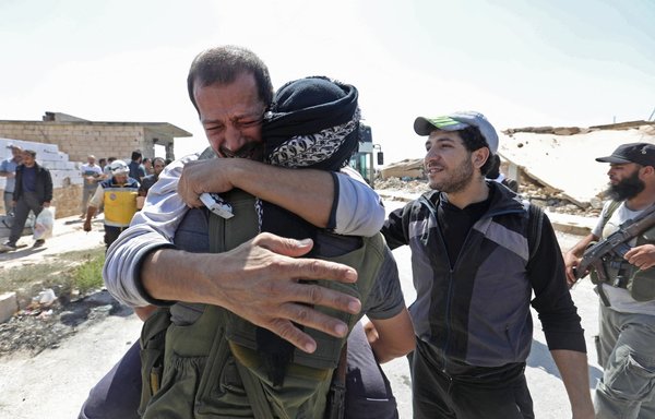 A Syrian prisoner released from a regime jail reacts as he embraces an opposition fighter upon his arrival at the al-Eis crossing point south of Aleppo on July 19, 2018. [Omar Haj Kadour/AFP]