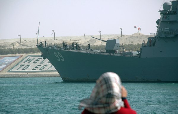 In this file photo from March 8, 2013, a woman takes pictures of the USS Winston Churchill crossing the Suez Canal off the coast of Ismailia port city. [AFP]