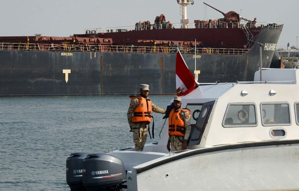 Egyptian coast guards patrol as a ship navigates the Suez Canal on March 30. [Tarek Wajeh/AFP]