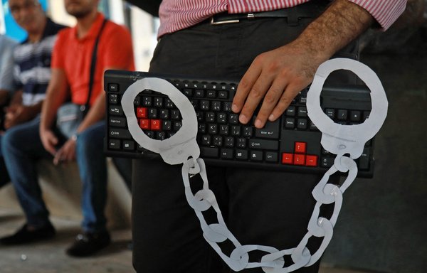 An activist holds a computer keyboard and makeshift handcuffs in downtown Beirut on July 24, 2018, during a protest against a recent wave of interrogations by Lebanese security forces of people making political comments on social media. [Anwar Amro/AFP]