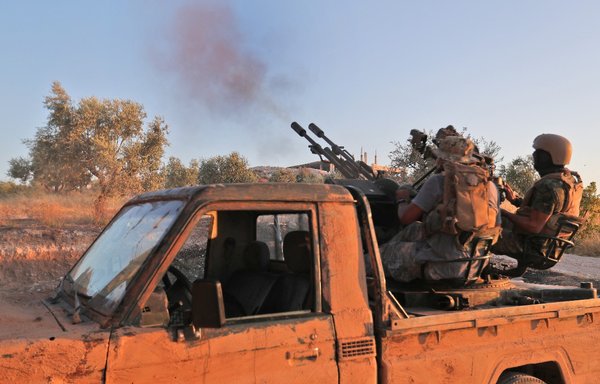 Fighters from Tahrir al-Sham fire an anti-aircraft gun mounted on a pickup truck in Syria's Idlib province on August 7, 2019. [Omar Haj Kadour/AFP]