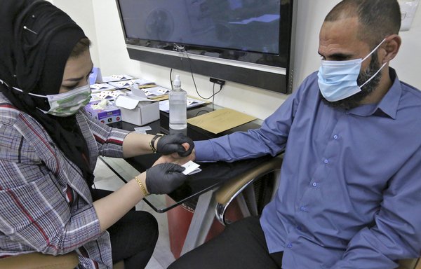 کارشناسان پزشکی قانونی عراق روز ۱۹ خرداد در بغداد نمونه های خون خانواده های عراقی هایی که اجسادشان در گورهای جمعی به وجود آمده توسط داعش در بادوش پیدا شده است، جمع آوری می کنند تا هویت این قربانیان را شناسایی کنند. [صباح عرعر/خبرگزاری فرانسه]