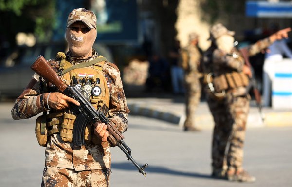 In this file photo taken October 26, 2019, fighters with Iraqi paramilitaries stand guard during a funeral procession in Baghdad. [Ahmad al-Rubaye/AFP]