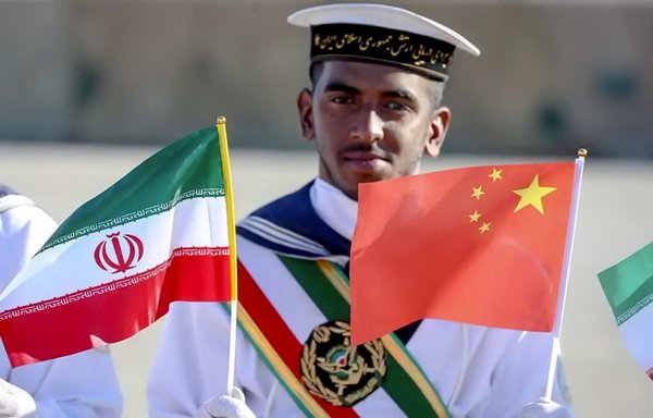 An Iranian sailor waves Chinese and Iranian flags during the arrival of a Chinese warship in Iran in 2019. [Iranian Ministry of Defence]
