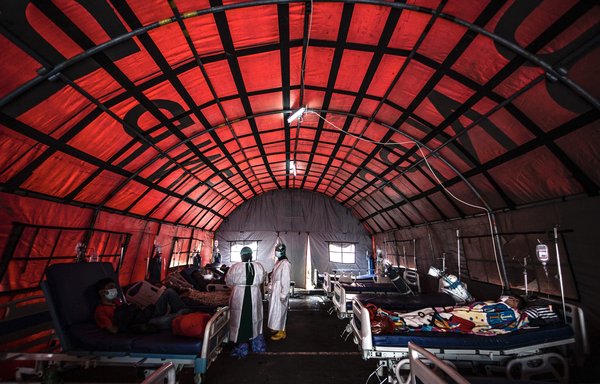 Medical personnel tend to COVID-19 patients in a tent set up outside a hospital in Bogor on June 29, as infections soar in Indonesia. [Aditya AjiAFP]
