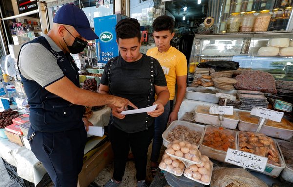 A member of the Iraqi Interior Ministry's anti-'fake news' team speaks to a shopkeeper in Baghdad on May 20, as part of a campaign to spread awareness among the population about the danger and legal consequences of fake news that often circulate on social media. [Ahmad al-Rubaye/AFP]