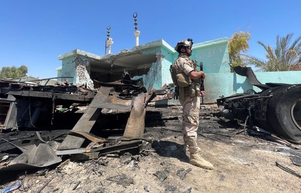 A member of the Iraqi security forces stands by a destroyed vehicle that was carrying rockets used to target Ain al-Asad base in al-Baghdadi district, Anbar province. [Ayman Henna/AFP]