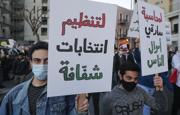 Lebanese protesters lift placards demanding transparency in elections and accountability for public fund misappropriation, as they march in downtown Beirut on March 12. [Joseph Eid/AFP]