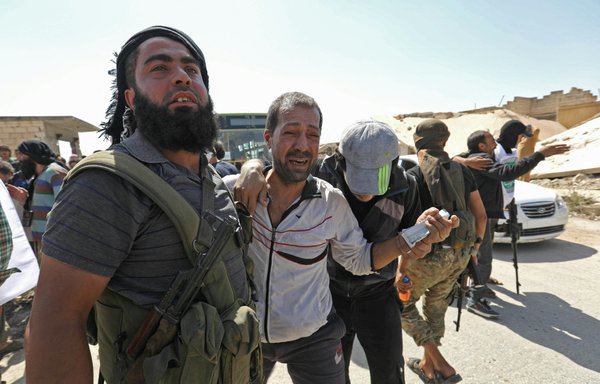 A Syrian prisoner released from a regime jail is surrounded by opposition fighters upon his arrival at al-Eis crossing point south of Aleppo on July 19, 2018. [Omar Haj Kadour/AFP]