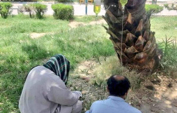 صورة التقطت في مدينة إيرانشهر بمحافظة سيستان وبلوشستان ونُشرت على وسائل التواصل الاجتماعي يوم 5 تموز/يوليو لمرضى لم تظهر عليهم أعراض كوفيد-19 وتم إخراجهم من مستشفى قريب لتلقي علاج بالمصل الوريدي في ظل حرارة ملتهبة.