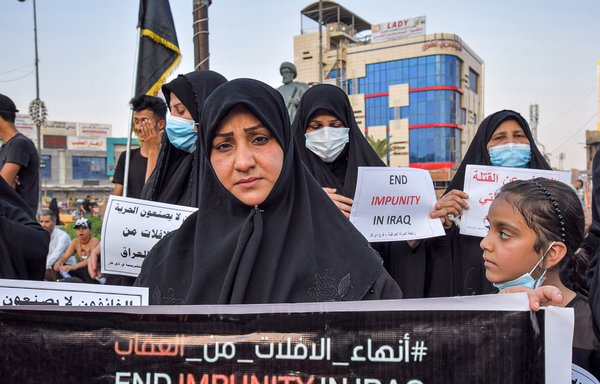 Women hold signs demanding authorities to hold accountable the killers of dozens of activists during a demonstration at Haboubi Square in Iraq's southern city of Nasiriyah on July 18. [Asaad Niazi/AFP]