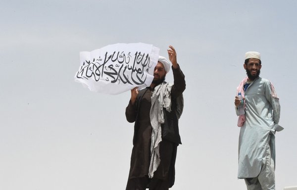 رجل يقف في 17 تموز/يوليو الجاري على الجانب الأفغاني من الحدود الأفغانية-الباكستانية، وهو يحمل علم طالبان. [باناراس خان/وكالة الصحافة الفرنسية]