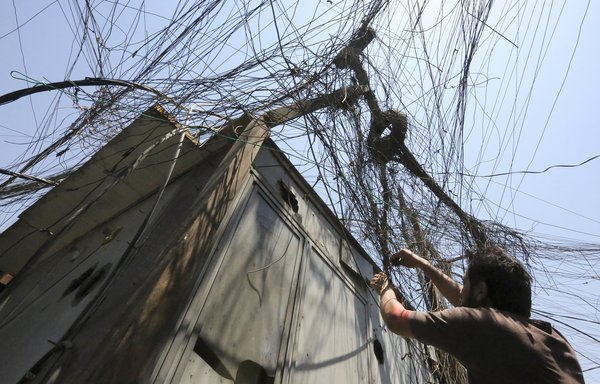 عراقي يعمل في 16 تموز/يوليو على تركيب كابلات لمولد كهربائي خاص بمدينة الصدر في بغداد، يمد عدة منازل بالطاقة عند انقطاع التيار الكهربائي. [صباح عرار/وكالة الصحافة الفرنسية]