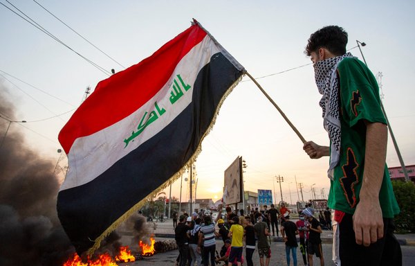 شاب يلوح بالعلم الوطني خلال تظاهرة في مدينة البصرة الجنوبية بتاريخ 14 تموز/يوليو 2020، فيما قطع المتظاهرون الطريق تنديدا بانقطاع الكهرباء والخدمات. [حسين فالح/وكالة الصحافة الفرنسية]