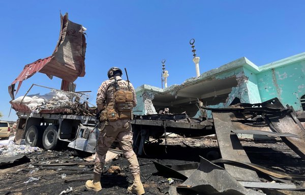 A member of the Iraqi forces walks past a destroyed vehicle that was carrying rockets hidden among sacks of flour in Anbar's al-Baghdadi district on July 8, a day after 14 rockets were fired at Ain al-Asad air base, causing minor injuries to two people and damaging local homes and a mosque. [Ayman Henna/AFP]