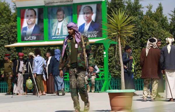 A pro-Houthi fighter visits the grave of slain Houthi political chief Saleh al-Samad in Sanaa on January 11. The portraits behind him show al-Samad, Houthi leader Abdul Malik al-Houthi, and Mahdi al-Mashat, who replaced the slain political leader. [Mohammed Huwais/AFP]