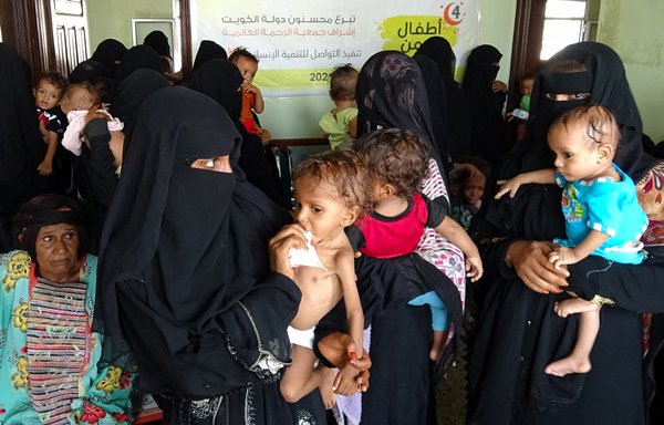 Yemeni women carry malnourished children as they wait at a clinic in the war-ravaged western province of al-Hodeidah on August 7. [Khaled Ziad/AFP]